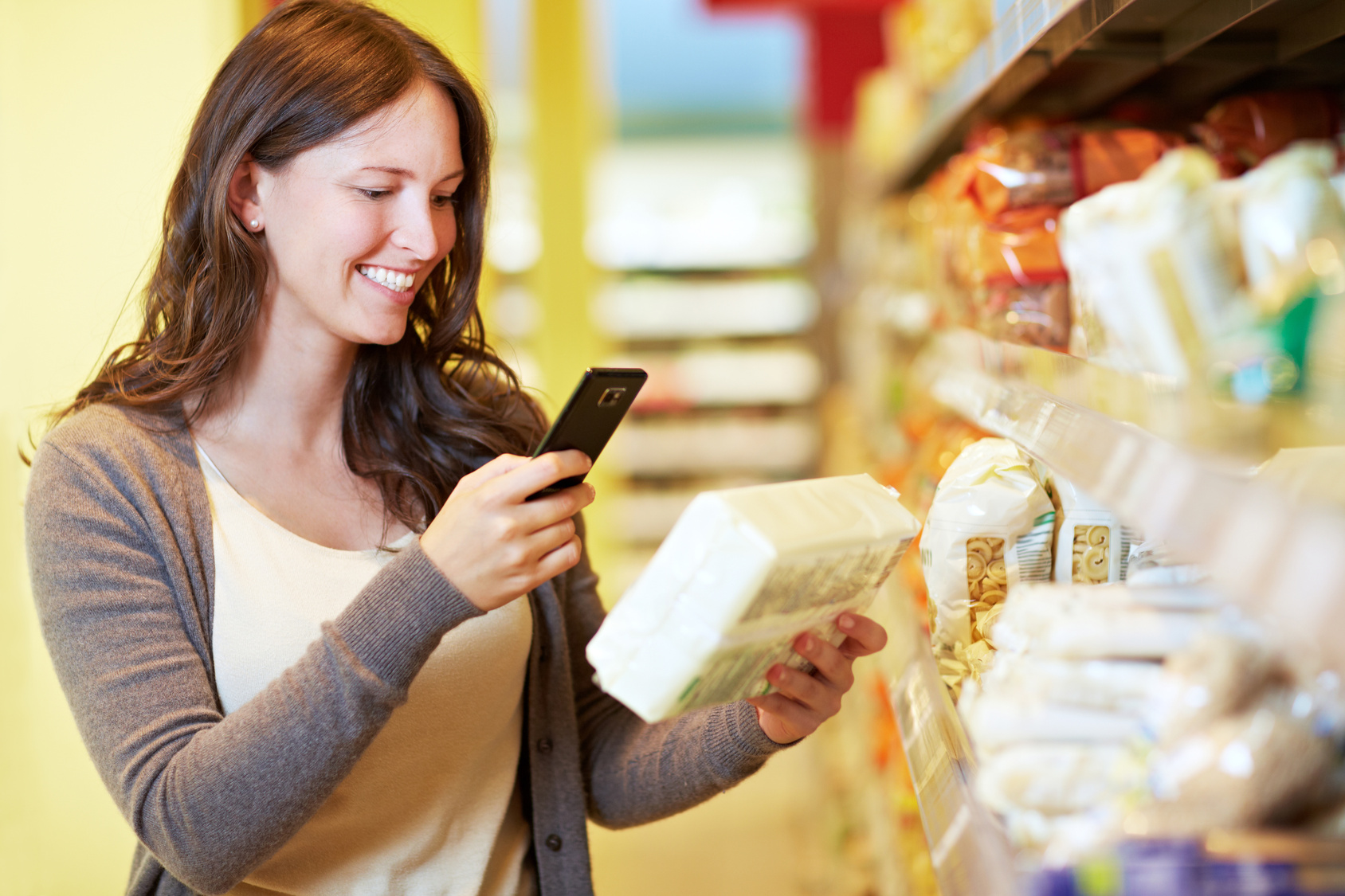 Lächelnde Frau scannt den Barcode eines Produkts im Supermarkt