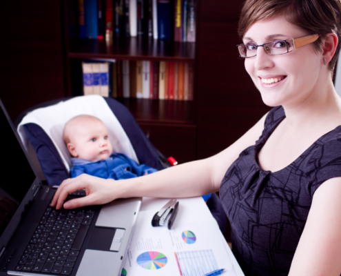 Geschäftsfrau, die mit ihrem Baby an einem Laptop arbeitet