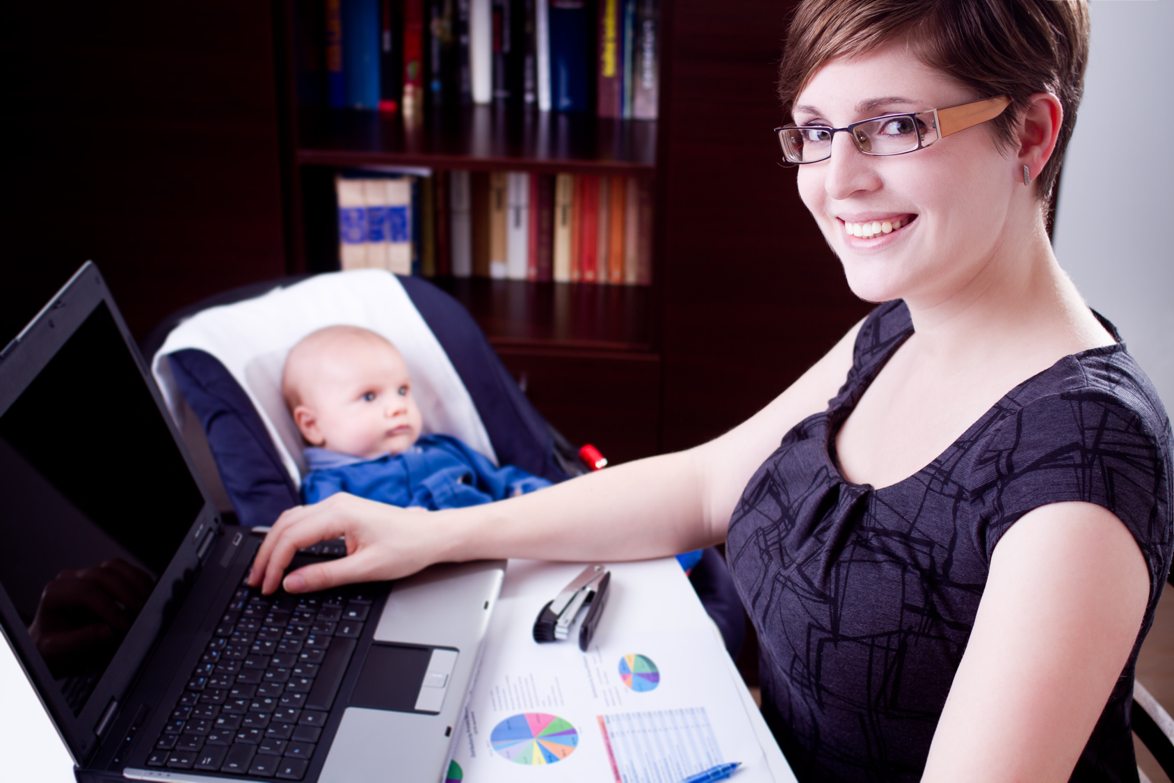 Geschäftsfrau, die mit ihrem Baby an einem Laptop arbeitet